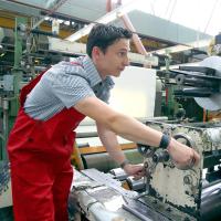 Ein Kunststoff- und Kautschuktechnologe bedient eine Maschine zum Zuschneiden von Kunststofffolie.