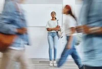 Junge Frau steht nachdenklich in einer Berufsschule