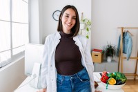 Eine Diätassistentin steht an ihrem Schreibtisch, auf dem sie gesunde Lebensmittel für die Patientengespräche vorbereitet hat.