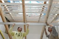 Ein Ausbaufacharbeiter und ein Meister für Ausbau verlegen Platten im Dachgeschoss vom Bildungs- und Technologiezentrum der Handwerkskammer zu Leipzig.