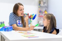 Eine Logopädin übt mit einem Vorschulkind die korrekte Aussprache von Silben.