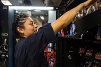 Eine Automatenfachfrau befüllt einen Lebensmittelautomaten mit Snacks und Süßigkeiten.