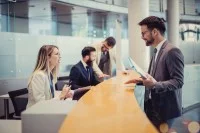 Eine Bankkauffrau berät einen Geschäftskunden am Schalter.