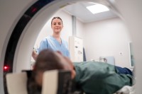 Eine medizinische Technologin für Radiologie begleitet einen Patienten bei der MRT-Untersuchung. 