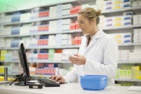 Eine pharmazeutisch-technische Assistentin recherchiert den Warenbestand eines Hautpflegeprodukts.