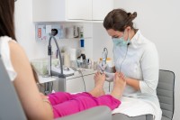 Eine Podologin behandelt die Füße einer Patientin.