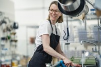 Eine Assistentin für Ernährung und Versorgung putzt die Küchenspüle in einem Heim für Menschen mit Behinderungen.
