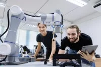Eine technische Assistentin testet mit einem Techniker in einem Labor den Prototyp eines neuen Roboters.