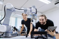 Eine technische Assistentin erprobt gemeinsam mit einem Techniker den Prototyp eines neuen Roboters.