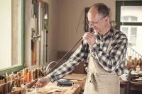 Ein Bogenmacher prüft in seiner Werkstatt einen noch unbespannten Bogen.