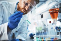 Ein chemisch-technischer Assistent untersucht im Labor eine Probe mit verschiedenen chemischen Reagenzien.