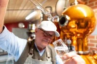 Ein Brenner kontrolliert in seiner Brennerei den von ihm gebrannten Gin.