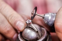 Ein Designer für angewandte Formgebung, Schmuck und Gerät repariert den Diamantring einer Kundin.