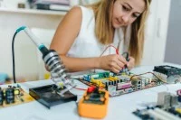 Eine elektrotechnische Assistentin schließt zwei Elektroden an eine Leiterplatte an.