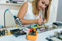 Eine elektrotechnische Assistentin baut auf einer Leiterplatte eine neue Versuchsanordnung auf. 