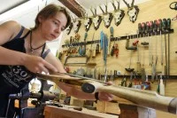 Eine Büchsenmacherin arbeitet in ihrer Werkstatt an einem Nußholzschaft für einen Kunden.