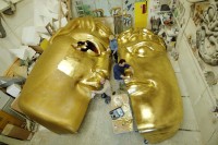 Bühnenplastiker arbeiten an einer riesigen Maske, die aus Kunststoff geschnitzt, mit Fiberglas überzogen und mit Blattgold vergoldet wurde.