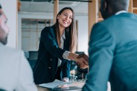 Eine Fremdsprachenkorrespondentin begrüßt zwei ausländische Geschäftspartner.