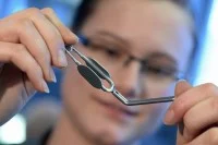 Eine Chirurgiemechanikerin des Medizintechnik-Herstellers Aesculap prüft einen Gefäßclip.