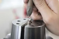 Ein Edelsteinfasser setzt einen Edelstein in einen Verlobungsring ein.