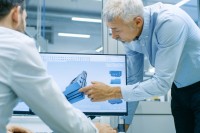 Ein Assistent für Maschinenbautechnik bespricht mit einem Ingenieur die Detailkonstruktion einer Maschine. 