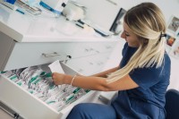 Eine medizinische Dokumentationsassistentin sucht eine Krankenakte aus dem Schrank heraus. 