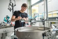 Ein Elektroniker für Geräte und Systeme arbeitet konzentriert an der Verschlauchung eines Industrieroboters.