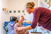 Eine Pflegeassistentin wäscht ein Mädchen, welches in einer Wohngemeinschaft für pflegebedürftige Menschen lebt.