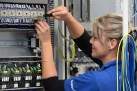 Eine Elektronikerin für Maschinen und Antriebstechnik arbeitet an einer Steuerungseinheit in einem Werk für Kombinationstechnik in Chemnitz.