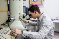 Ein physikalisch-technischer Assistent misst eine Probe am Elektronenmikroskop.