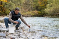 Ein umweltschutztechnischer Assistent untersucht die Wasserqualität eines Fließgewässers.