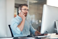 Ein kaufmännischer Assistent/ Wirtschaftsassistent für E-Business Management stimmt sich telefonisch mit einem Geschäftspartner ab.