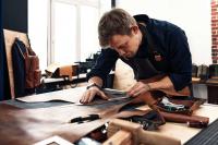 Eine Fachkraft für Lederverarbeitung vermisst in der Werkstatt Leder für die Herstellung von Rucksäcken.