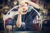 Ein Fahrradmonteur baut in seiner Werkstatt neue Speichen in die Felge eines Fahrradrads ein.