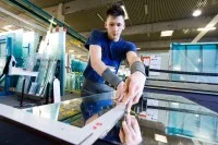 Ein Flachglastechnologe schneidet in der Glaserei Flachglas mit einem Diamantschneider.