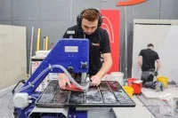 Ein Fliesen-, Platten- und Mosaikleger schneidet eine Fliese zu.