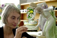 Eine Glas- und Porzellanmalerin retuschiert in der Restaurierwerkstatt der Staatlichen Porzellan-Manufaktur Meissen eine neue Hand an der Figur "Die Kugelspielerin".