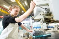 Eine Glasveredlerin bohrt ein Loch in ein Flachglas.