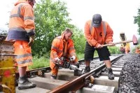 Mehrere Gleisbauer verbinden beim Bahnhof Eyach eine neue Weiche mit den Gleisen.