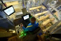 Ein Holzbearbeitungsmechaniker verarbeitet im Sägewerk mit einer automatischen Säge einen Baumstamm zu Brettern.