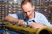 Ein Holzblasinstrumentenmacher arbeitet an einem Baritonsaxophon.