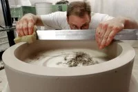 Ein Mitarbeiter der Porzellanfabrik Hermsdorf prüft und korrigiert die Oberfläche eines Werkstücks aus Rohware, das für eine Porzellanmühle zum Mahlen von Hartstoffen bestimmt ist.