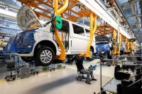 Ein Karosserie- und Fahrzeugbaumechaniker arbeitet unter einem Transporter im Werk von Volkswagen Nutzfahrzeuge.