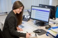 Eine Kauffrau für Kurier-, Express- und Postdienstleistungen berechnet die Kosten für Liefertouren beim Paketdienstleister Hermes.