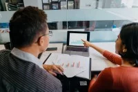 Zwei Kaufleute für Marketingkommunikation besprechen die Auswertung einer Marktforschung.