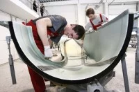 Zwei Leichtflugzeugbauer arbeiten an der Rumpfschale eines Motorflugzeuges vom Typ Aquila A210 auf dem Flughafengelände in Schönhagen.