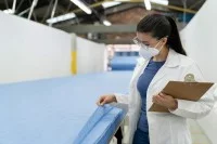 Eine Produktprüferin - Textil begutachtet die Qualität eines SMS-Vliesstoffes für Medizinprodukte.