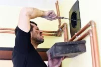 Ein Schornsteinfeger reinigt ein Rohr.