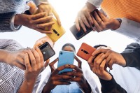 Junge Menschen stehen mit ihren Smartphones im Kreis