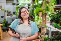 Frau mit Down-Syndrom arbeitet in einem Blumenladen mit Tablet